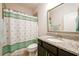 Well-lit bathroom featuring a granite vanity top, framed mirror, and a shower with decorative curtain at 4041 Woodward Walk Ln, Suwanee, GA 30024