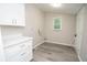 Well-organized laundry room with a storage cabinet, utility sink, and clean gray flooring at 1889 Vesta Ave, Atlanta, GA 30344