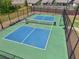 Aerial view of a blue and green outdoor pickleball court with black fencing, benches, and green space around it at 3382 Long Creek Dr, Buford, GA 30519