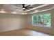 Bedroom featuring tray ceiling, fan, wood floors, and large window providing ample natural light and view at 2167 Main Nw St, Atlanta, GA 30318
