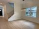 Open-concept living room with wood floors, modern lighting fixture, stairway, and large window providing natural light at 2167 Main Nw St, Atlanta, GA 30318