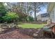A serene backyard with a cozy fire pit, wicker seating, and well-manicured lawn surrounded by mature trees at 6355 Stallion Dr, Cumming, GA 30040