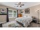 A cozy bedroom with a ceiling fan, a large window, and a comfortable bed with striped bedding at 6355 Stallion Dr, Cumming, GA 30040