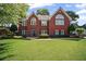 Traditional brick home with a well-maintained lawn and mature landscaping at 6355 Stallion Dr, Cumming, GA 30040