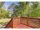 Charming back porch with a wood lattice railing offers a serene view of the lush backyard and surrounding trees at 3527 Starwood Sw Trl, Lilburn, GA 30047