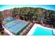 Aerial view of well-maintained tennis courts next to a blue swimming pool surrounded by lush trees at 3527 Starwood Sw Trl, Lilburn, GA 30047