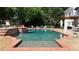 A refreshing in-ground pool with brick accents and a small waterfall feature is surrounded by patio furniture at 5045 Harrington Rd, Johns Creek, GA 30022