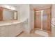 Well-lit bathroom featuring a large framed mirror, white cabinets, and a walk-in shower with glass doors at 5045 Harrington Rd, Johns Creek, GA 30022