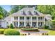 Elegant white home featuring a symmetrical design, stately columns, and mature landscaping at 5045 Harrington Rd, Johns Creek, GA 30022