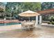 Relaxing outdoor patio area with a dining table under an umbrella next to a beautiful pool with a waterfall feature at 5045 Harrington Rd, Johns Creek, GA 30022