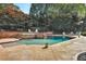 Inviting outdoor pool area with a waterfall feature, mature trees, and ample seating for relaxing poolside at 5045 Harrington Rd, Johns Creek, GA 30022