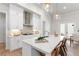 This open kitchen features white cabinets, stainless appliances, a quartz island with seating, and flows into the dining area at 515 Godfrey Dr, Cumming, GA 30040