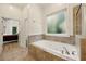 Bright bathroom featuring a soaking tub with jets and a decorative tile surround near a window at 3380 Canon Bay Dr, Cumming, GA 30041