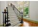 Staircase with black wrought iron railing and carpeted steps with lots of light from large windows at 3380 Canon Bay Dr, Cumming, GA 30041