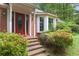 Elegant red front door with glass detail, brick facade, bay window, and professionally landscaped yard at 491 Hemlock Sw Dr, Marietta, GA 30064