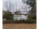 Quaint home with a visible foundation, set amidst lush trees and foliage in the backyard at 2010 Mcafee Pl, Decatur, GA 30032