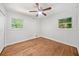 Bright bedroom featuring a ceiling fan, hardwood floors, and two windows letting in natural light at 2683 Stardust Trl, Decatur, GA 30034
