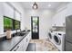 Well-lit laundry room with modern appliances, dark countertops, and herringbone flooring at 604 Trinity Church Rd, Canton, GA 30115
