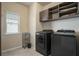 Functional laundry room featuring appliances and overhead cabinets at 113 Osier Dr, Mcdonough, GA 30252