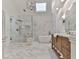 Luxurious bathroom with walk-in glass shower, soaking tub, wood vanity, and marble-patterned tile at 139 Grandmar Chase, Canton, GA 30115
