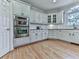 Bright kitchen with stainless steel double ovens, white cabinets, granite countertops, and hardwood floors at 139 Grandmar Chase, Canton, GA 30115