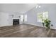 Open living room with wood floors, a fireplace, a ceiling fan, and multiple windows at 6597 Ivy Log Dr, Austell, GA 30168