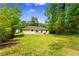 Large backyard with lush green lawn, mature trees, and exterior view of the home's facade at 4002 Lindsey Dr, Decatur, GA 30035