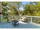 Outdoor deck with seating featuring chairs and a cushioned bench around a black table, surrounded by lush greenery at 435 Webb Dr, Norcross, GA 30071