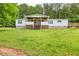 A single-story home features a front porch, wooden deck, green grass, and mature shade trees at 743 New Hope Rd, Lawrenceville, GA 30046