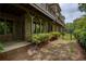 View of the townhome backyard, featuring patio, brick facade, and lush green landscaping at 385 Windy Pines Trl, Roswell, GA 30075