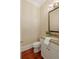 Clean, compact powder room with hardwood floors, granite countertop, a classic mirror, and a well-lit vanity at 385 Windy Pines Trl, Roswell, GA 30075