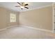 Neutral bedroom with plush carpet, ceiling fan, and a window letting in natural light at 385 Windy Pines Trl, Roswell, GA 30075