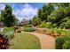 A manicured community park featuring several benches, stone walls, walkways, and lush landscaping at 385 Windy Pines Trl, Roswell, GA 30075