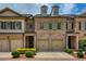 Charming brick townhome with a two-car garage, complemented by manicured landscaping and classic architectural details at 385 Windy Pines Trl, Roswell, GA 30075