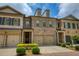 Charming brick townhome with a two-car garage, complemented by manicured landscaping and classic architectural details at 385 Windy Pines Trl, Roswell, GA 30075