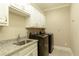 Well-lit laundry room with granite counters, cabinets, sink, and modern washer and dryer appliances at 385 Windy Pines Trl, Roswell, GA 30075