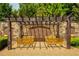 Close-up view of wooden pergola with seating area featuring multiple yellow benches and stone walls at 385 Windy Pines Trl, Roswell, GA 30075