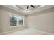 Bedroom with carpet flooring, natural light from windows, and a ceiling fan with tray ceiling at 1330 Adams Sw Dr, Atlanta, GA 30311