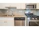 Close-up of modern kitchen with stainless steel appliances, granite countertops, and white cabinetry at 6082 Raintree Bnd, Lithonia, GA 30058