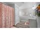 Bright bathroom featuring a shower with a pink curtain, wood-look floors and a vanity at 6263 Fernstone Nw Trl, Acworth, GA 30101