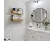 Stylish powder room featuring a round mirror, floating shelves, and modern fixtures at 6263 Fernstone Nw Trl, Acworth, GA 30101