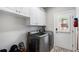 Functional laundry room with modern washer and dryer, white cabinets, and brick-look flooring at 6263 Fernstone Nw Trl, Acworth, GA 30101