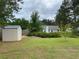 Spacious backyard featuring a storage shed, lush lawn, and mature trees, offering ample space for outdoor activities at 5298 Autumn Run Dr, Powder Springs, GA 30127