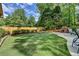 Expansive backyard featuring a well-maintained lawn, mature trees, and an outdoor fireplace at 5335 Bannergate Dr, Johns Creek, GA 30022
