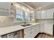 Updated kitchen boasts white cabinets, tile backsplash, stainless steel dishwasher, and quartz countertops at 5335 Bannergate Dr, Johns Creek, GA 30022