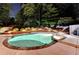 Backyard pool area with pool lights, brick retaining wall and wooded backdrop at 5335 Bannergate Dr, Johns Creek, GA 30022