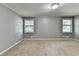This is a bedroom with neutral carpet, light gray walls, and natural light from two windows at 6419 Danbury Ln, Norcross, GA 30093