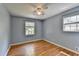 A light blue bedroom with hardwood floors, a ceiling fan, and two windows for natural light at 6419 Danbury Ln, Norcross, GA 30093