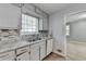 The eat-in kitchen features stone countertops, gray cabinets above the stainless steel sink with window and a dishwasher at 6419 Danbury Ln, Norcross, GA 30093