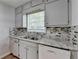 Kitchen area with stone countertops, patterned tile backsplash and gray cabinets above the stainless steel sink at 6419 Danbury Ln, Norcross, GA 30093